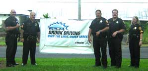Image: 5 officers pose next to a "drunk driving" sign