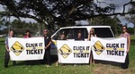 Image of sign wavers holding three large 'Click It or Ticket' signs