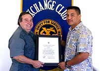 Photo: Officer Correa, holding a framed certificate stands between Chruchill and Estrell in front of the Exchange Club banner