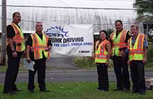 Image: officers and civilians standing by an anti-drunk driving sign.