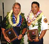 Image: Ishikawa and Uchida wearing leis and holding framed awards