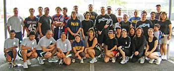 A large group of particpants stand while five squat in the front row.